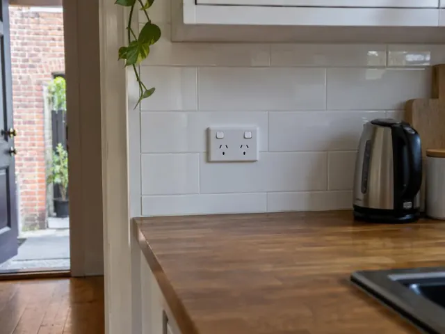 White tiled kitchen splashback with a double power point above a wooden benchtop in Rozelle